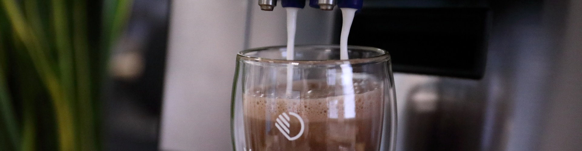Glas die gevuld wordt met warme chocomelk uit een Van Duijnen koffiemachine