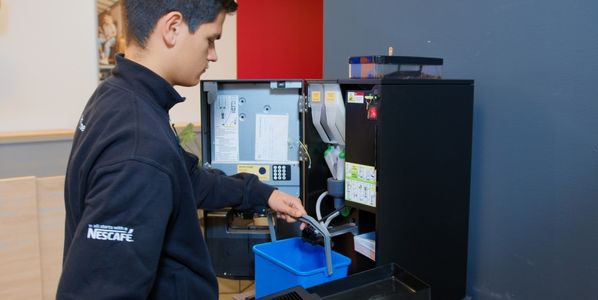 operator maakt koffiemachine schoon bij een bedrijf