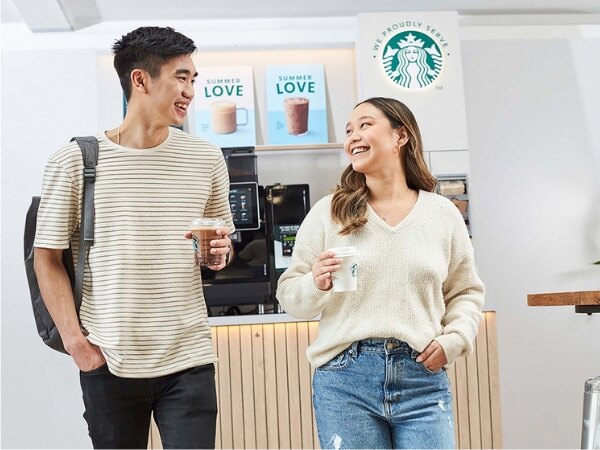 SB couple standing for booth holding coffee cup and chocolate milk cup